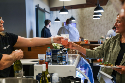 Roam event, a woman handing another woman a drink over the bar