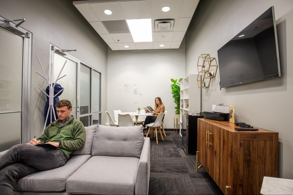 Two people sitting in a shared workspace.